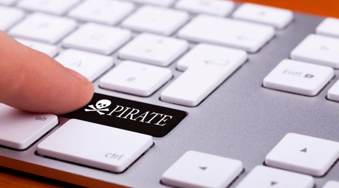 Dedo selecionando uma tecla preta escrito “pirate” em um teclado de computador com teclas brancas.