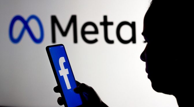 Pessoa segurando um celular com logo do Facebook e acessando as configurações de campanha do Facebook ads para provedores de internet.